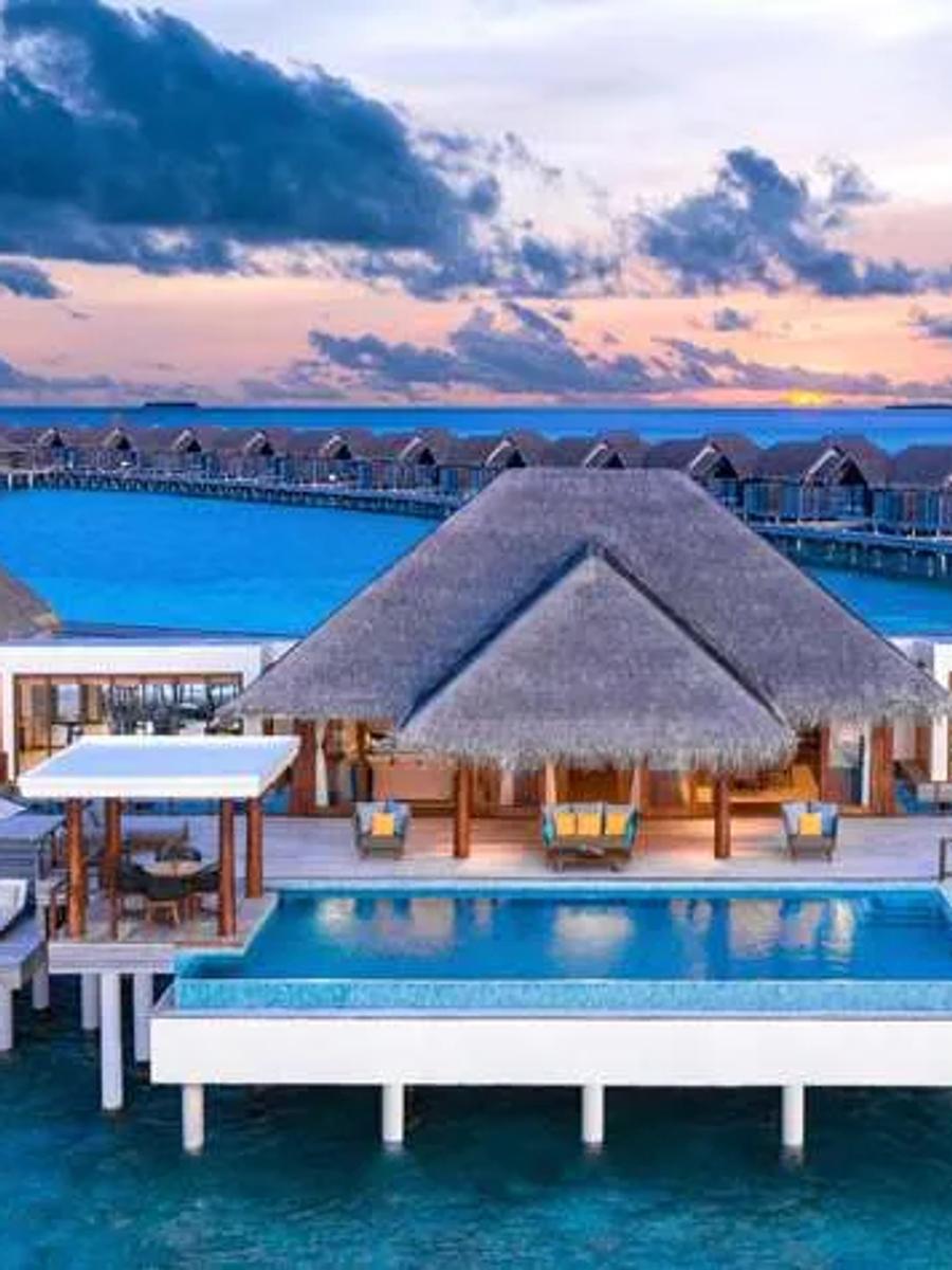 Two Bedroom Sunset Over Water Pool Residence at Anantara Kihavah, its pool and the overwater villa row beyond lit at dusk