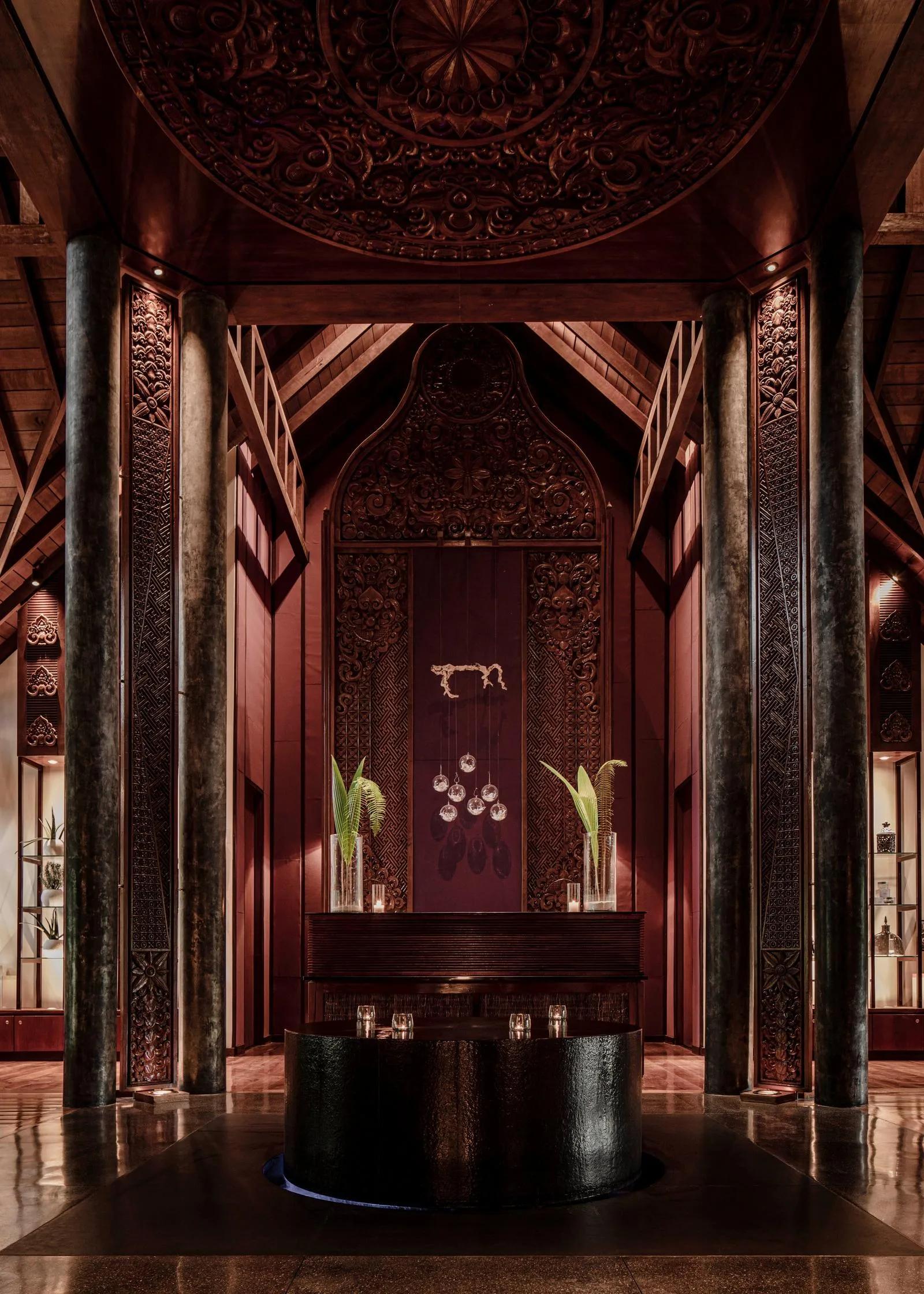 The hand-carved entrance doors and columns at One&Only Spa, Reethi Rah, lit for evening
