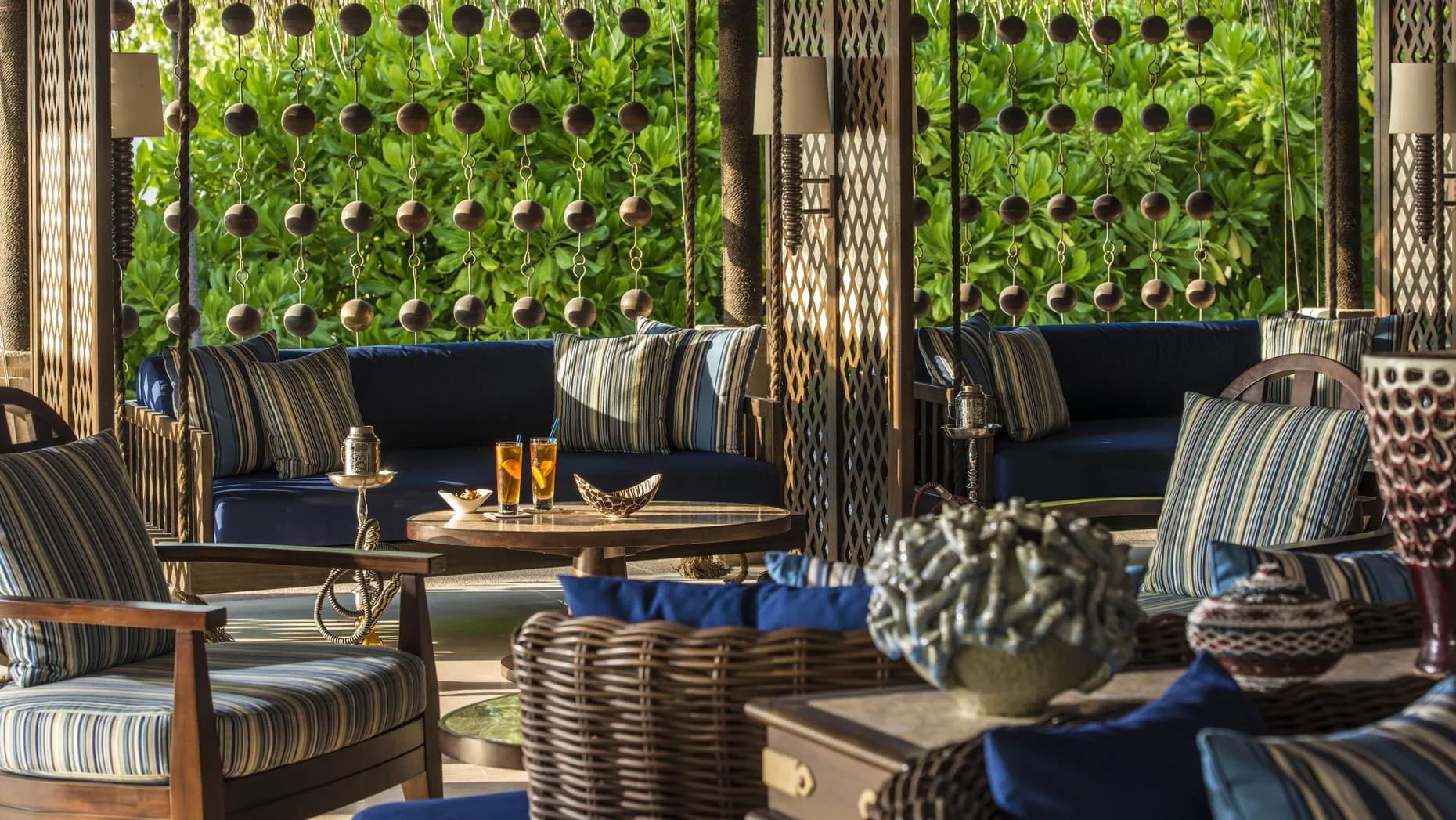 Sunset Lounge's shaded seating, striped cushions and hanging bead curtains against the greenery