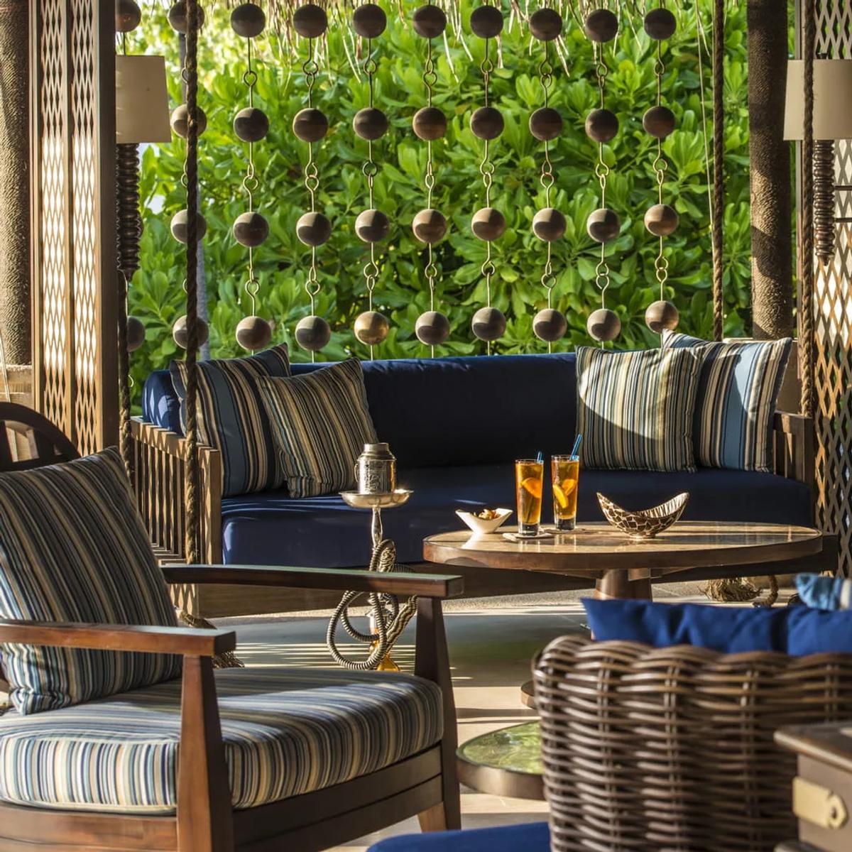 Sunset Lounge's shaded seating, striped cushions and hanging bead curtains against the greenery