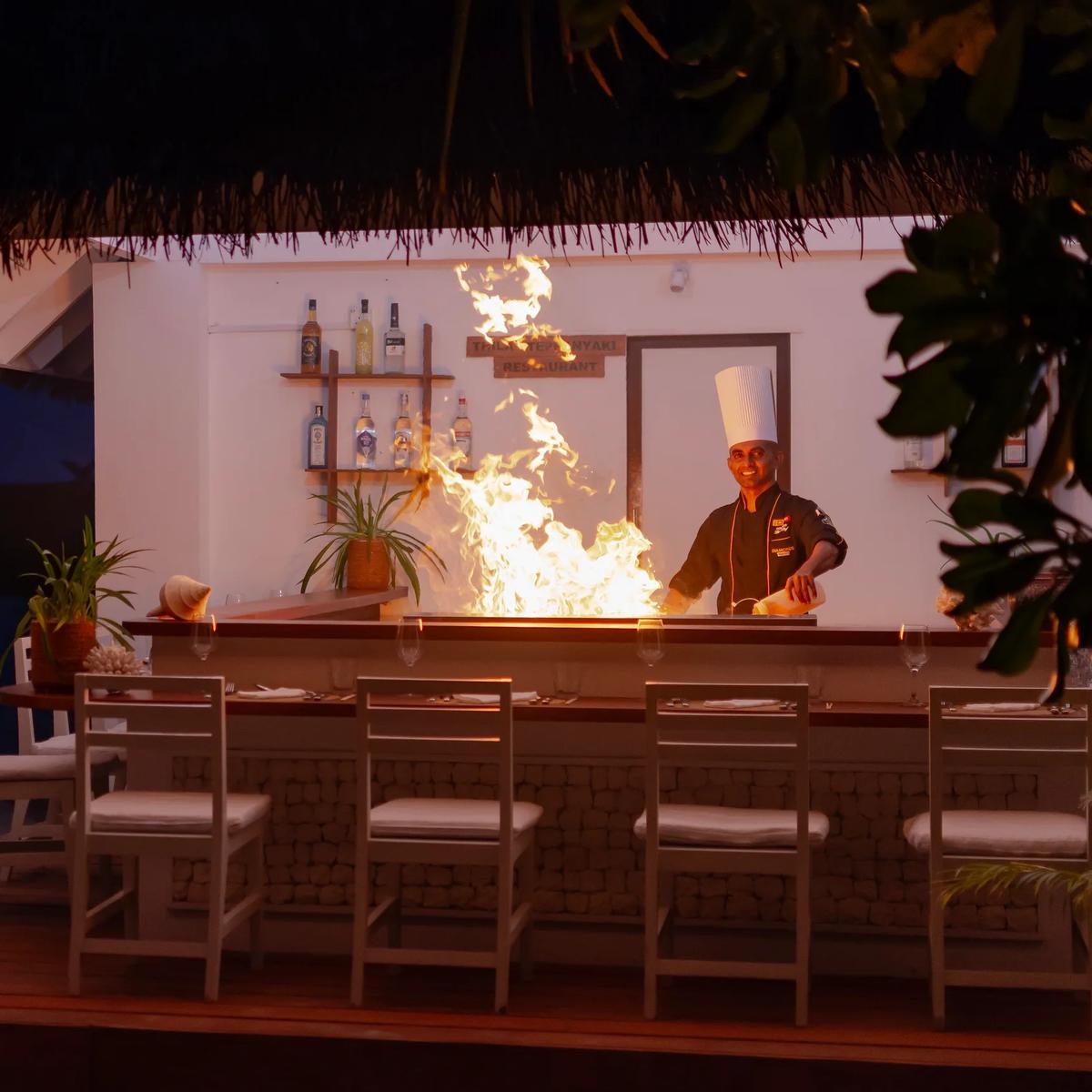 A chef performing teppanyaki live-cooking with a flame at Thila Japanese Restaurant, Diamonds Athuruga