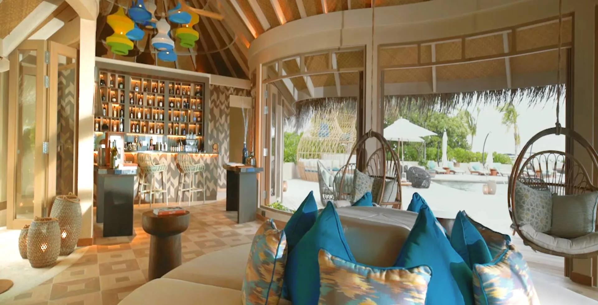 Naiboli's bar and lounge, with colourful pendant lights and a poolside swing chair visible outside.