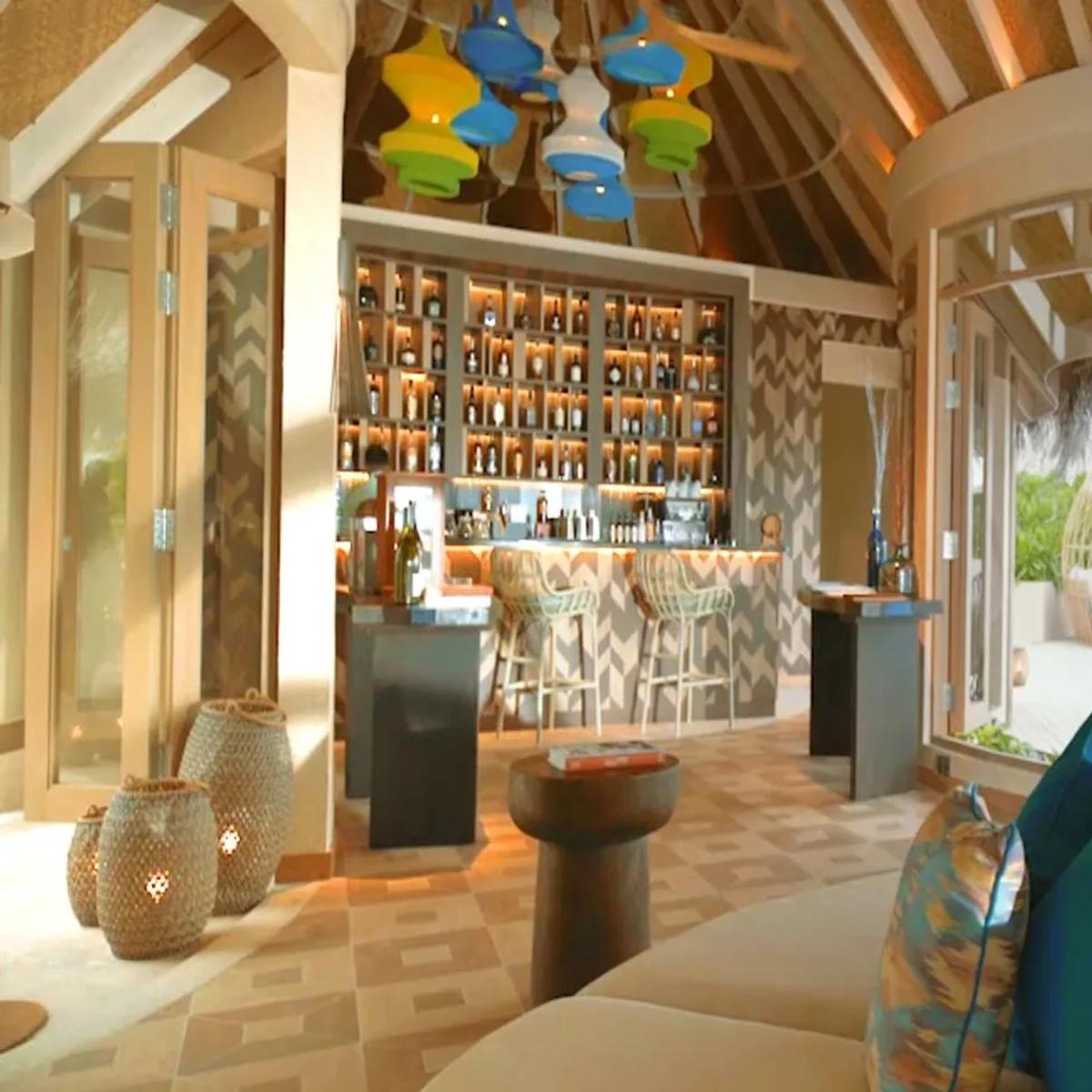 Naiboli's bar and lounge, with colourful pendant lights and a poolside swing chair visible outside.