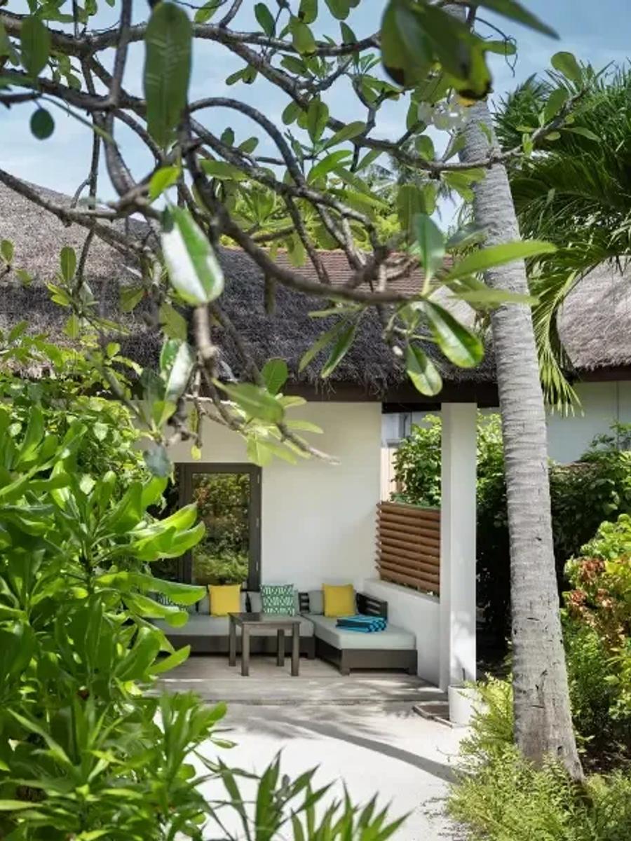 The Two Bedroom Deluxe Villa's outdoor lounge area, seen through the branches of a frangipani tree