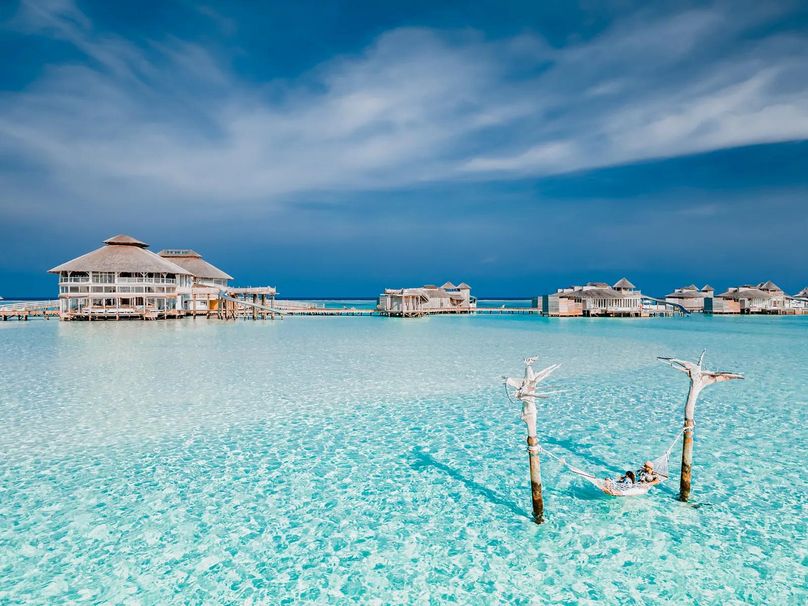 A quiet stretch of Maldivian beach at dusk, calm water meeting pale sand