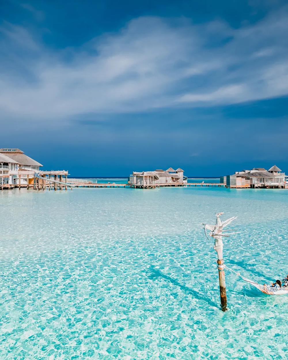 A quiet stretch of Maldivian beach at dusk, calm water meeting pale sand