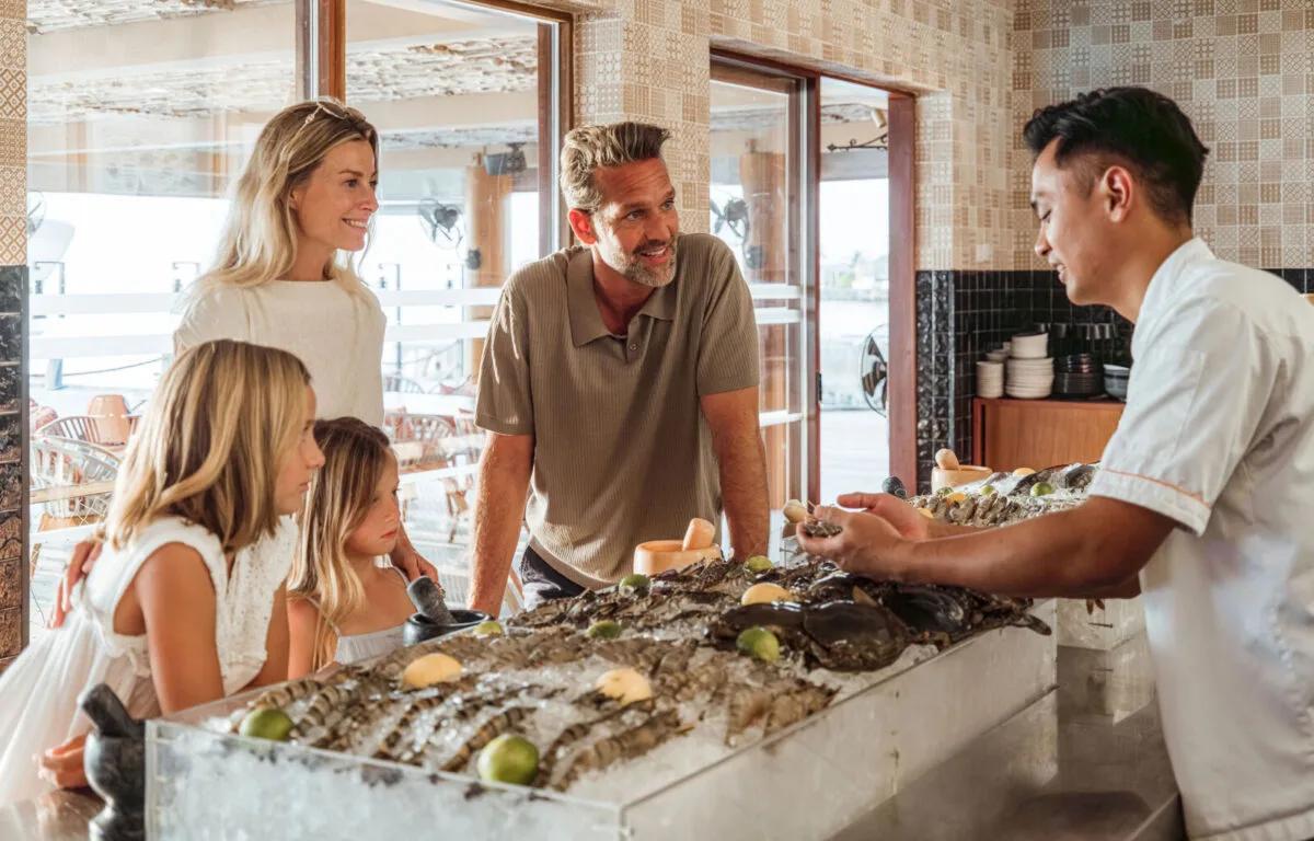 A chef plating a delicate seafood dish with tweezers at Fish Market