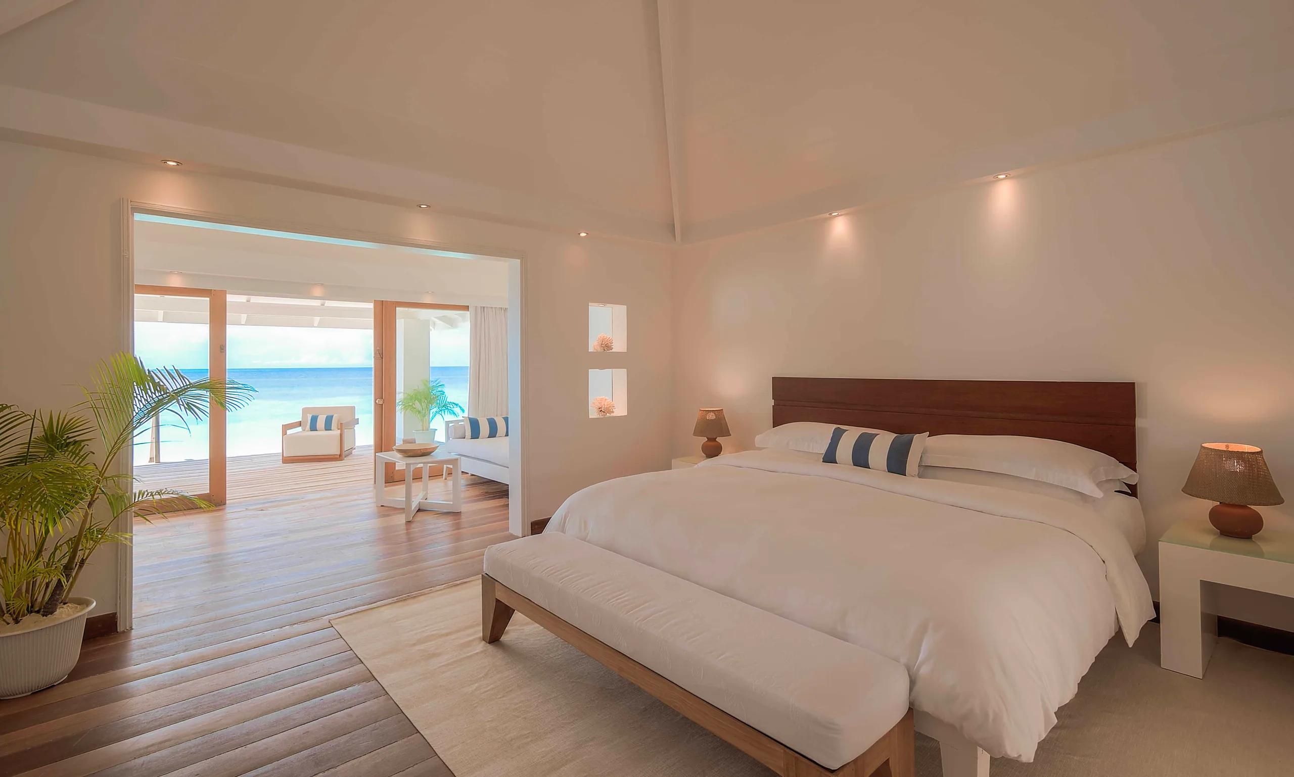 Bedroom of a Beach Front Junior Suite at Diamonds Athuruga, opening onto the beach