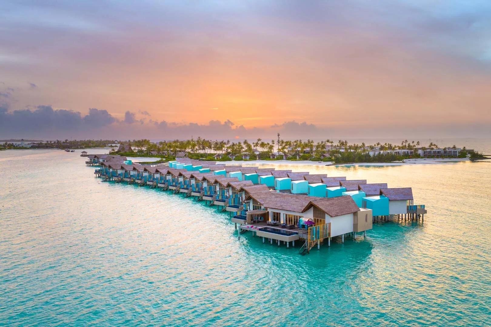 Hard Rock Hotel Maldives' beach and overwater villa jetty, seen from above with the lagoon beyond