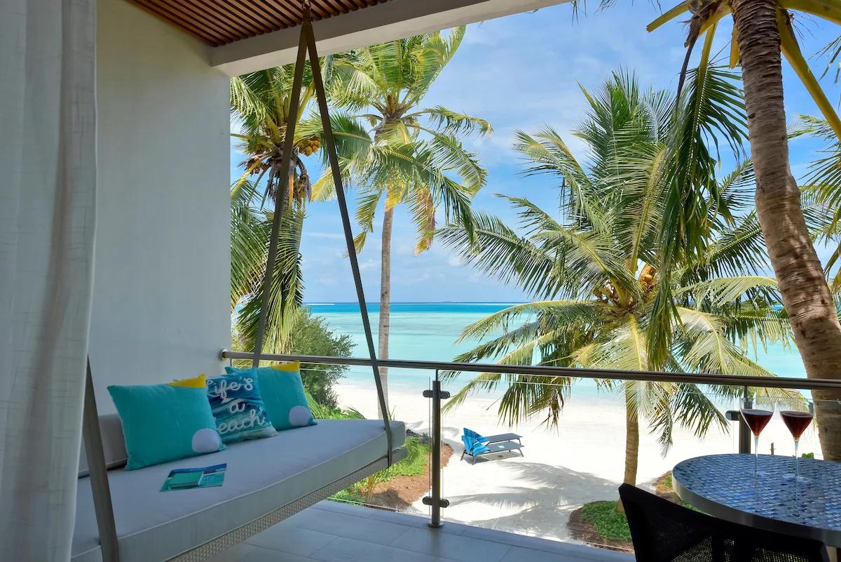 A Beach & Sky Studio's private terrace daybed and sea view through the palms