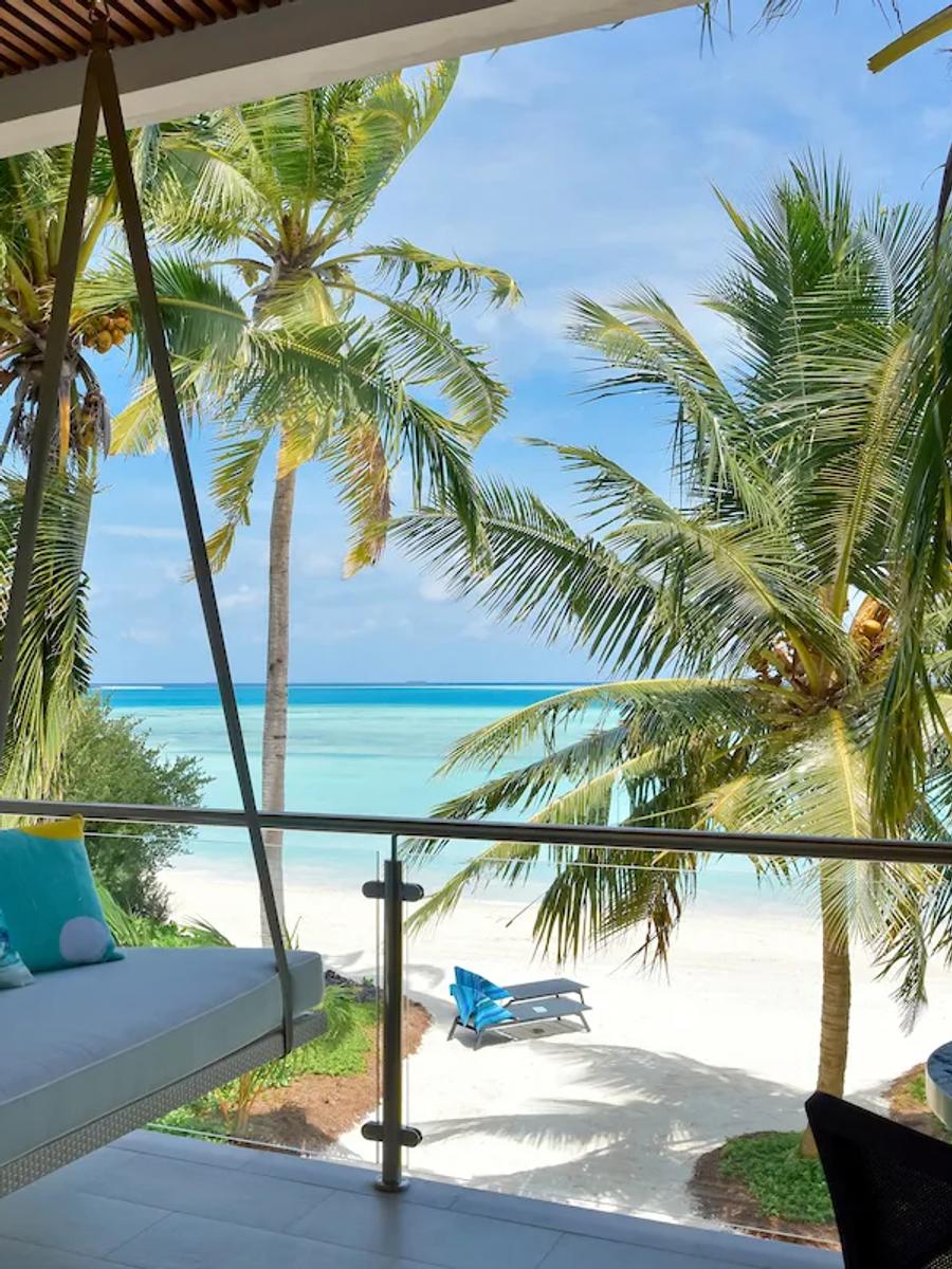 A Beach & Sky Studio's private terrace daybed and sea view through the palms