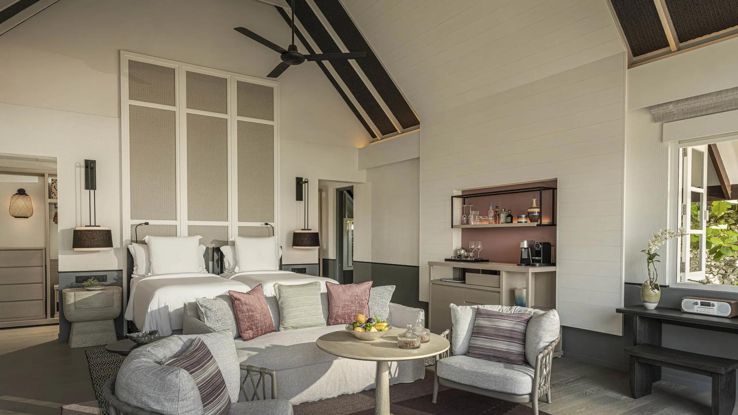 The twin-bed bedroom of a Two-Bedroom Oceanfront Villa, with its own wet bar and ceiling fan