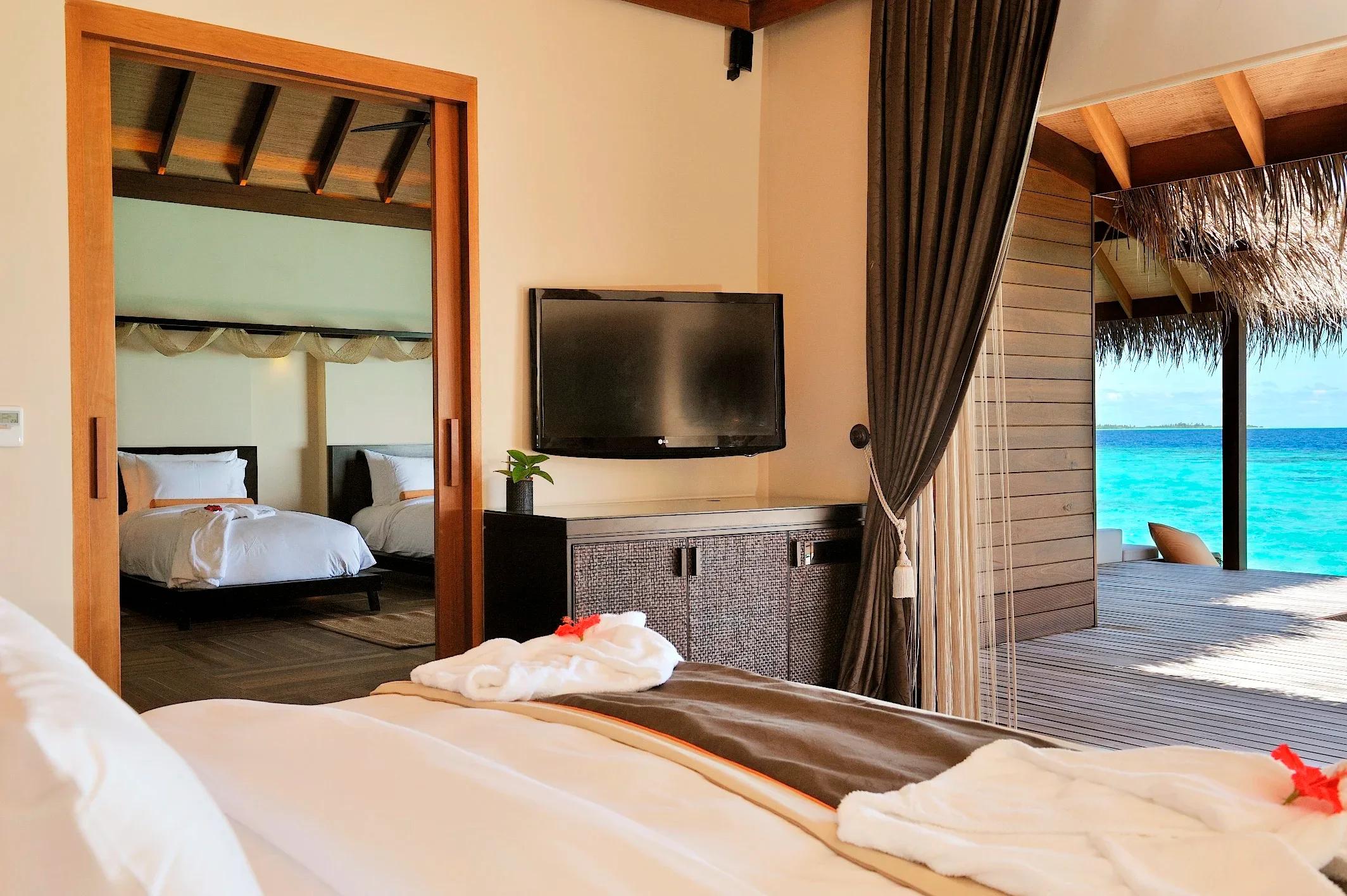 A Sunset Ocean Family Suite's main bedroom, with a second twin-bed room reflected through the doorway