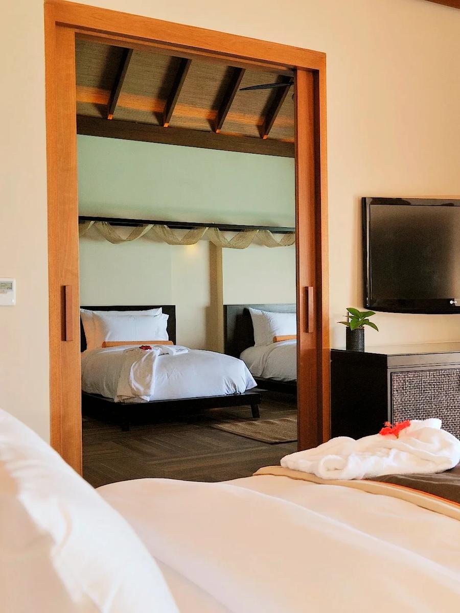 A Sunset Ocean Family Suite's main bedroom, with a second twin-bed room reflected through the doorway
