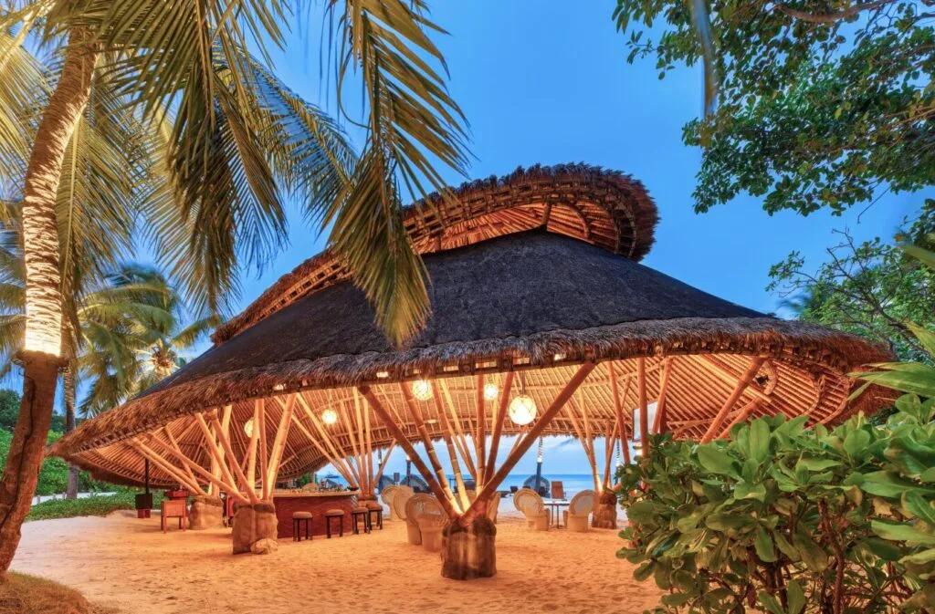 Onu Onu's domed bamboo bar structure on the beach at dusk, lit from within