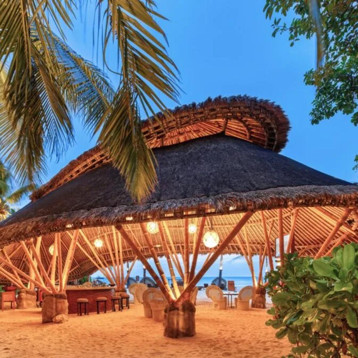 Onu Onu's domed bamboo bar structure on the beach at dusk, lit from within