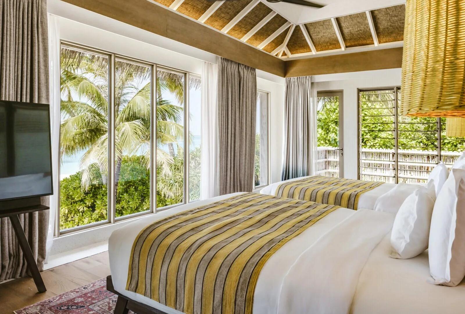 The two-storey exterior and private pool of a Two-Bedroom Beachfront Pool Residence, set among palms