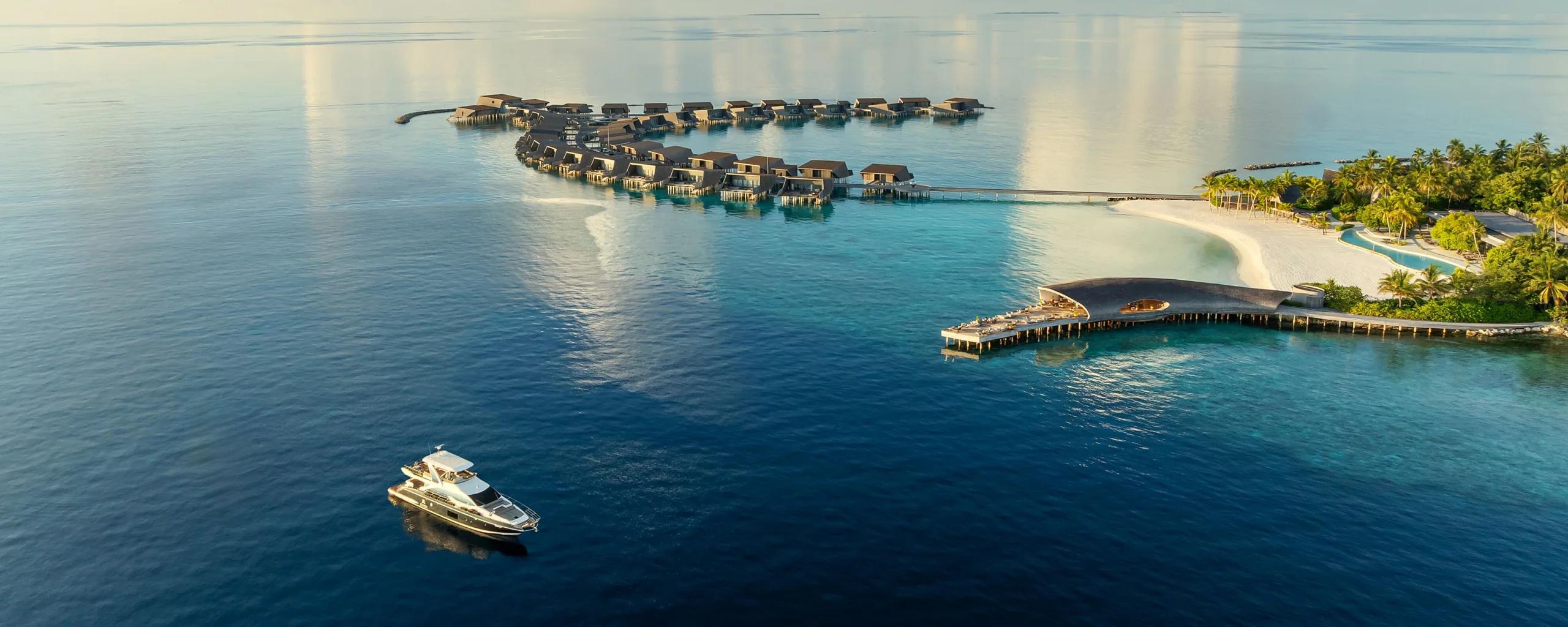 Aerial view of Vommuli Island's coastline meeting the open ocean horizon