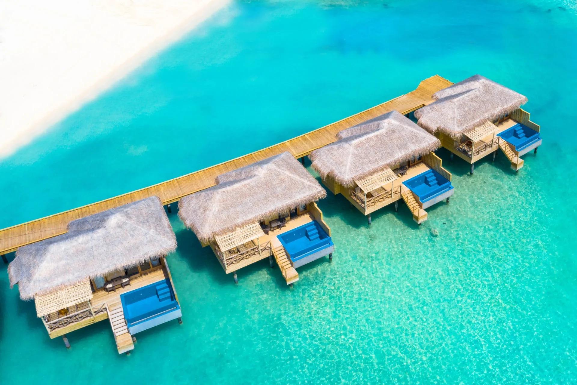 A second aerial view of You & Me Maldives, showing the island's overwater villas set against the reef