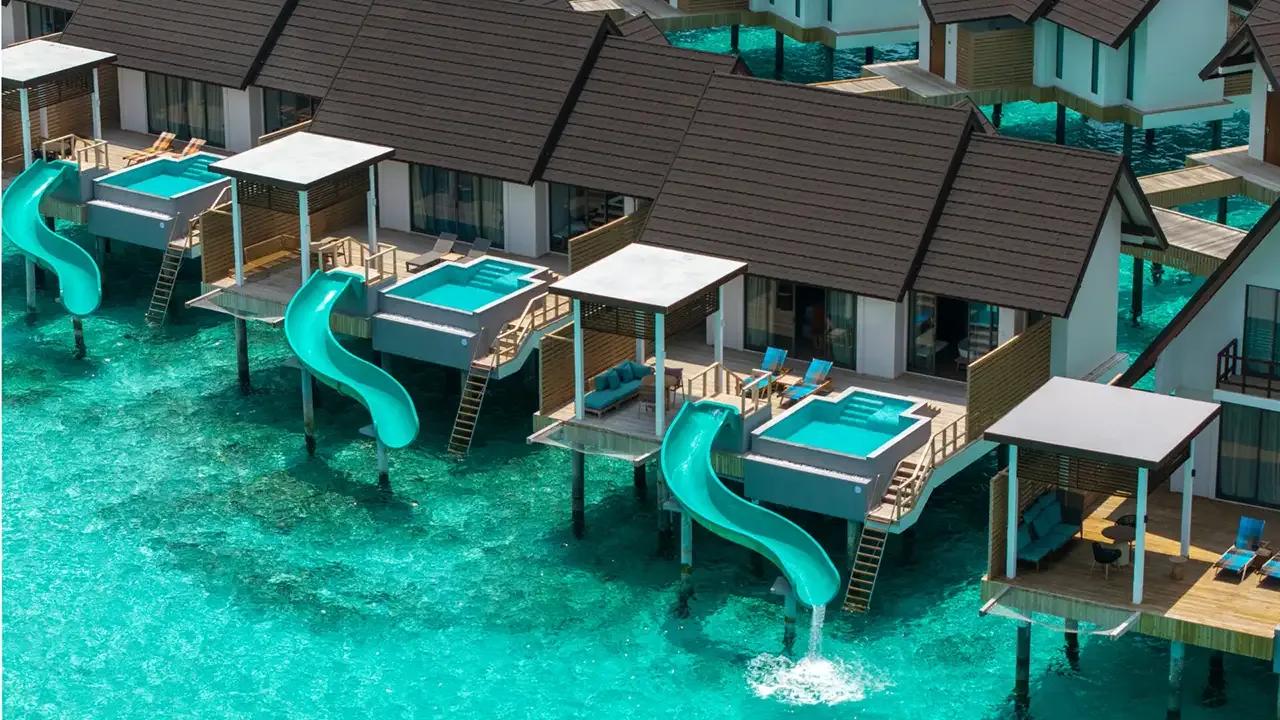 A Water Pool Villa with Slide, its pool slide dropping straight into the lagoon below the deck