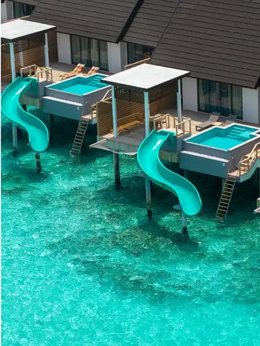 A Water Pool Villa with Slide, its pool slide dropping straight into the lagoon below the deck