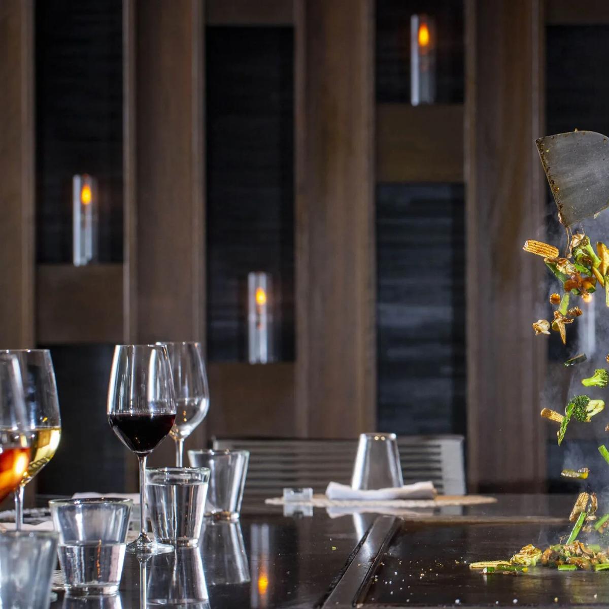 A chef tossing vegetables from the teppanyaki grill at Café Landaa