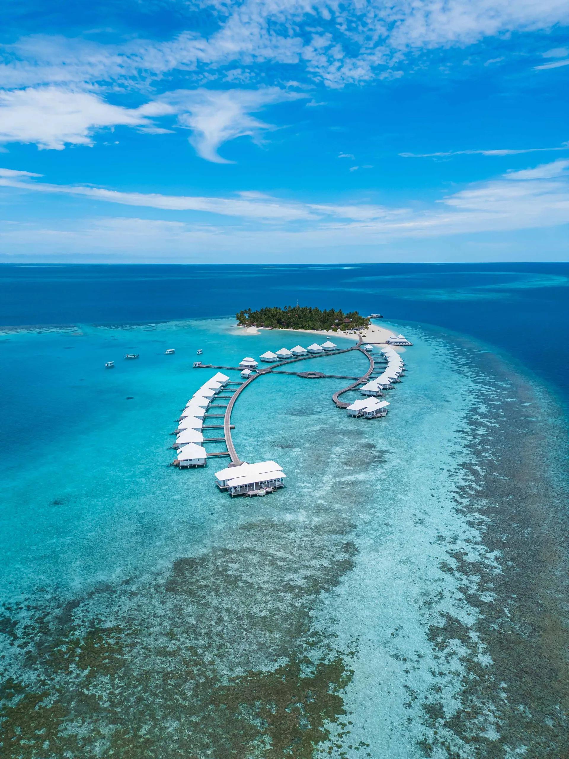 Aerial view of Diamonds Athuruga's island and water villa jetties curving out over the reef, South Ari Atoll