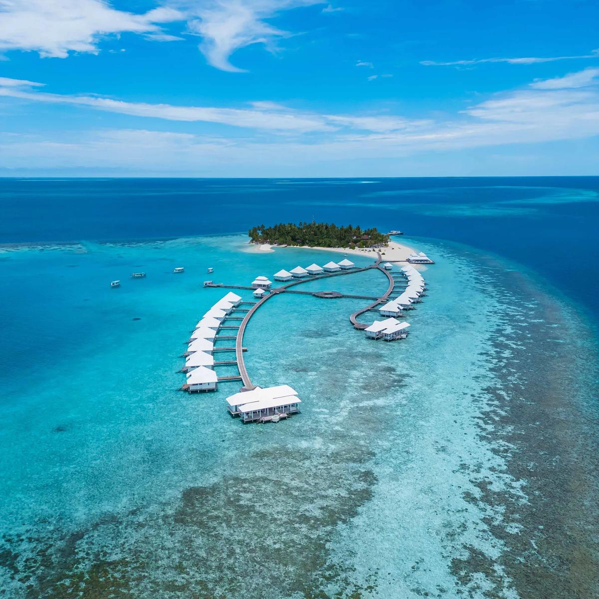 Aerial view of Diamonds Athuruga's island and water villa jetties curving out over the reef, South Ari Atoll