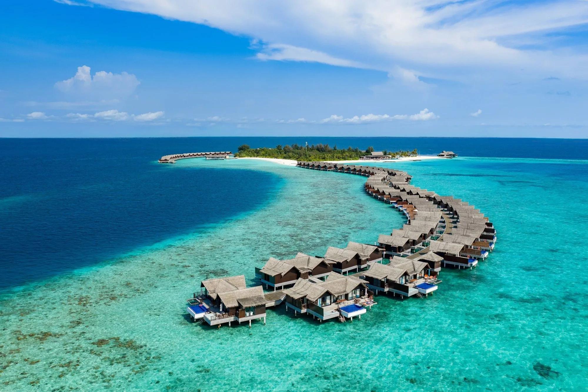 A top-down aerial view of Grand Park Kodhipparu's overwater villas and lagoon in North Malé Atoll
