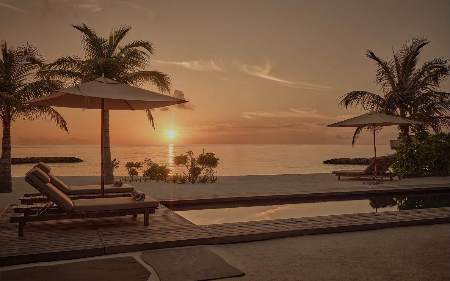 Loungers and a private pool at a One-Bedroom Sunset Beach Pool Villa, lit by the setting sun