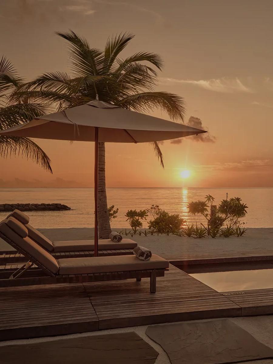 Loungers and a private pool at a One-Bedroom Sunset Beach Pool Villa, lit by the setting sun