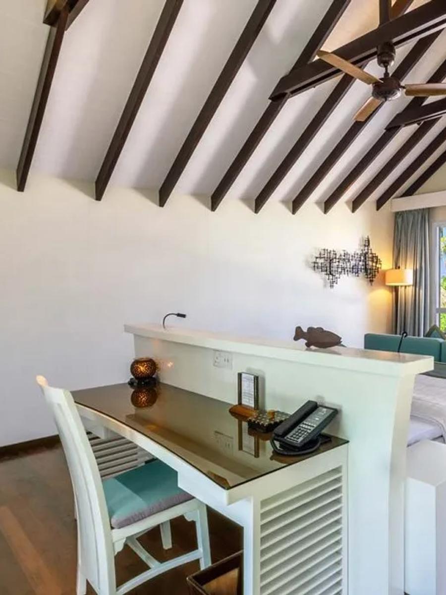 Deluxe Beach Villa interior with a dark-beamed ceiling, sofa, and sliding doors open to the beach