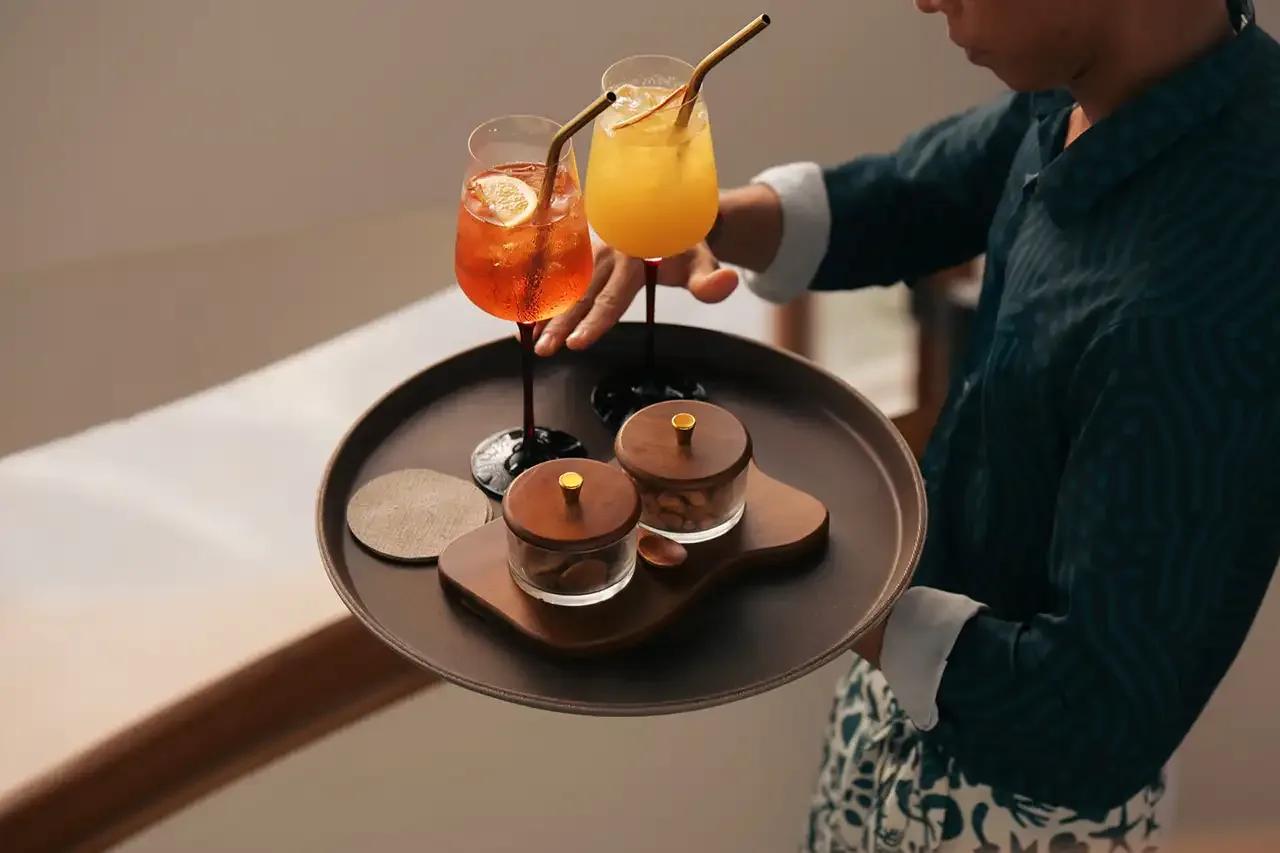 A server presenting a tray of Raagu's cocktails