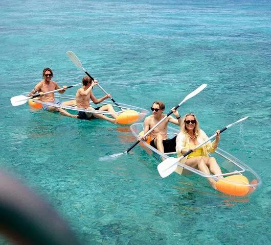 Clear-hulled kayaks crossing the shallow turquoise lagoon off Joali Being, the reef visible beneath the surface