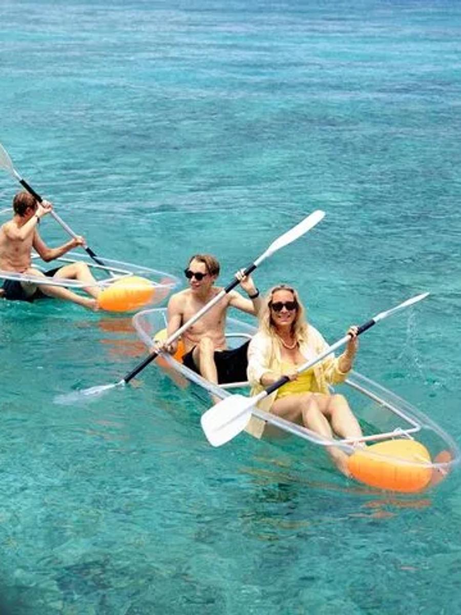 Clear-hulled kayaks crossing the shallow turquoise lagoon off Joali Being, the reef visible beneath the surface