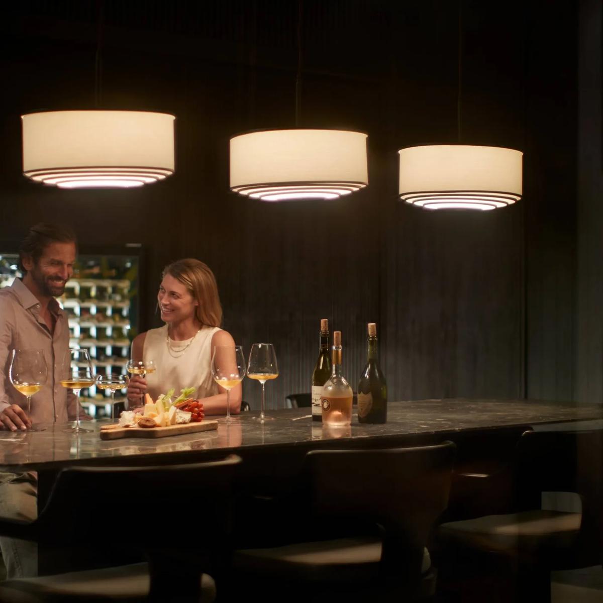 A couple at IWAU's marble bar, sampling wine and a cheese board beside the glass-walled cellar