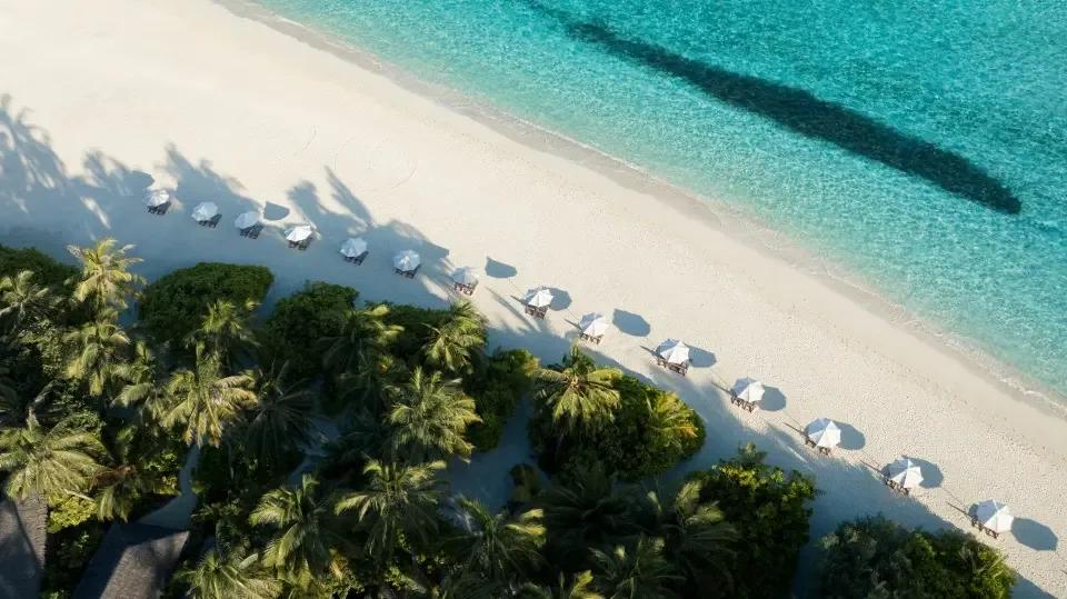Thatched sun-lounger cabanas lined along Velassaru's beach, seen from above