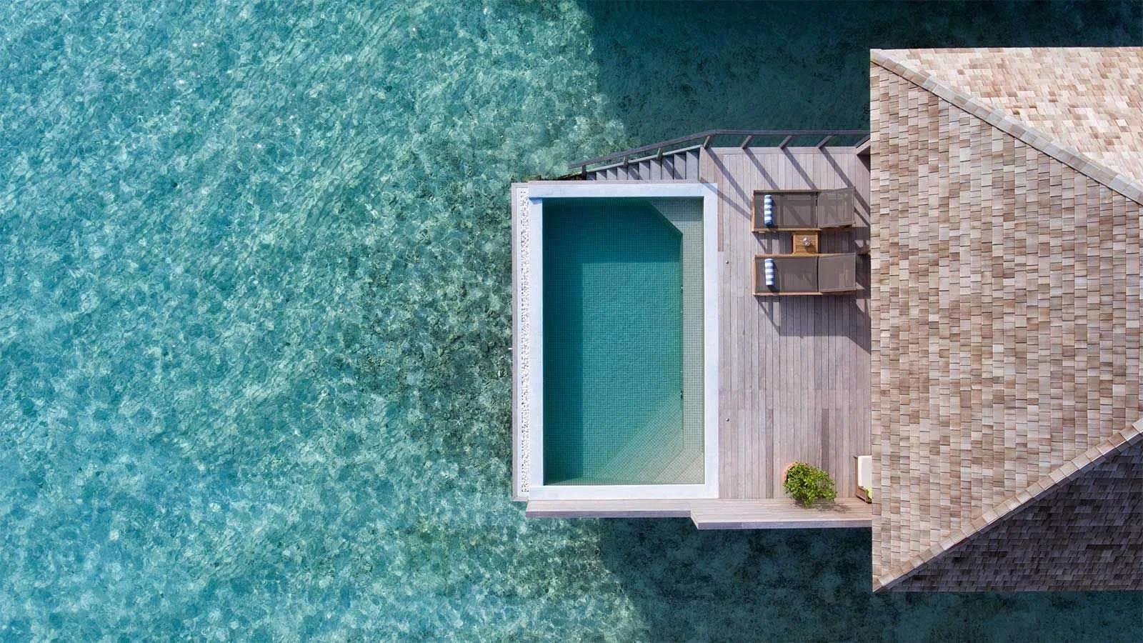 An Ocean Pool Villa's infinity pool seen from directly above, its far edge meeting the turquoise lagoon