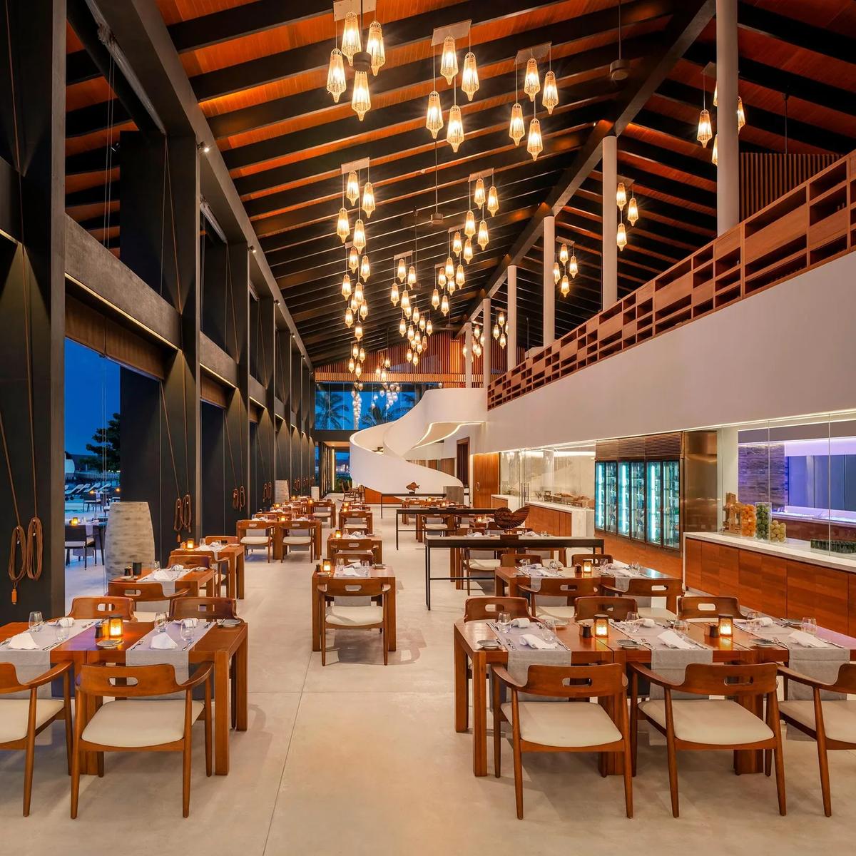 Island Kitchen's open-air dining hall in the evening, tables set beside the show kitchen