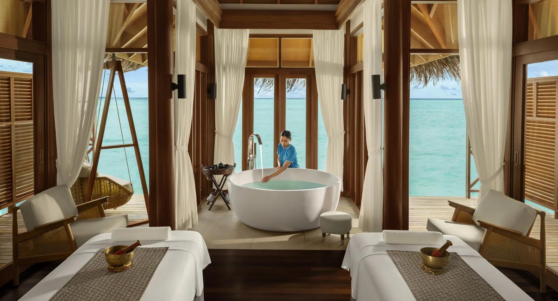 A twin treatment suite at the overwater Anantara Spa, with a freestanding tub and lagoon views