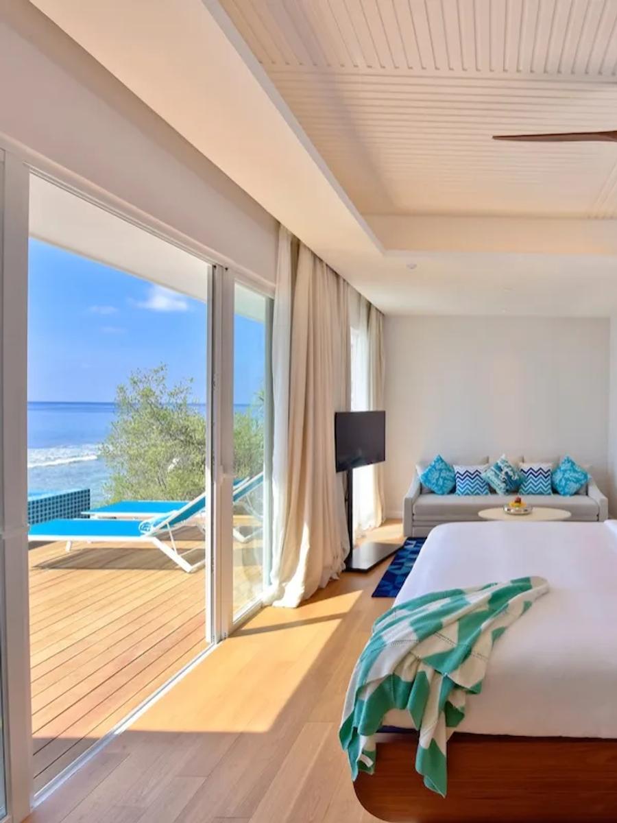 An Ocean Pool Villa's bedroom, with its private pool and deck visible through the sliding doors