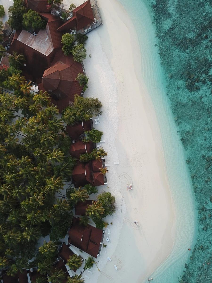 Aerial view of the white beach and coral reef near Diamonds Thudufushi's secluded Sandbank Junior Suites