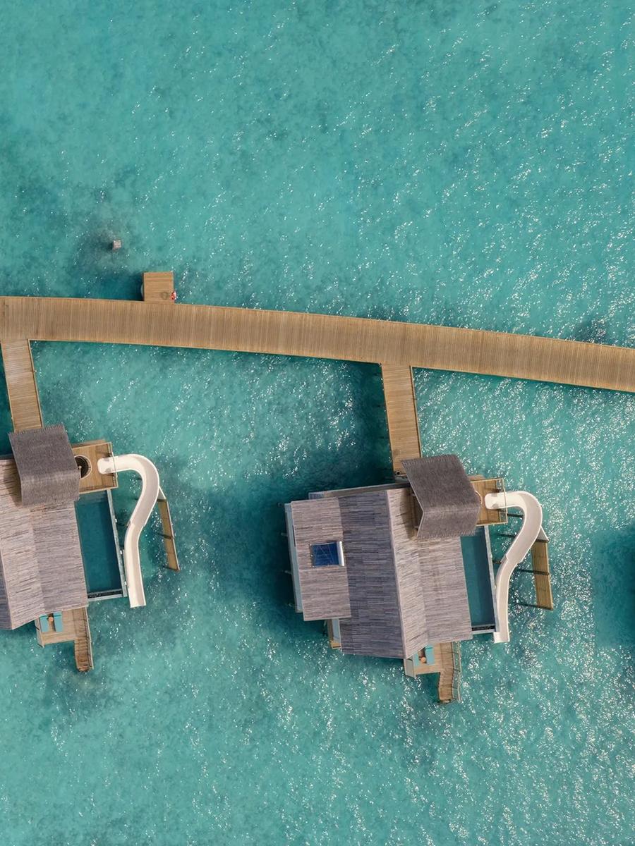 A Water Pool Villa with Slide at RAH GILI Maldives, overwater with a curved waterslide running into the lagoon