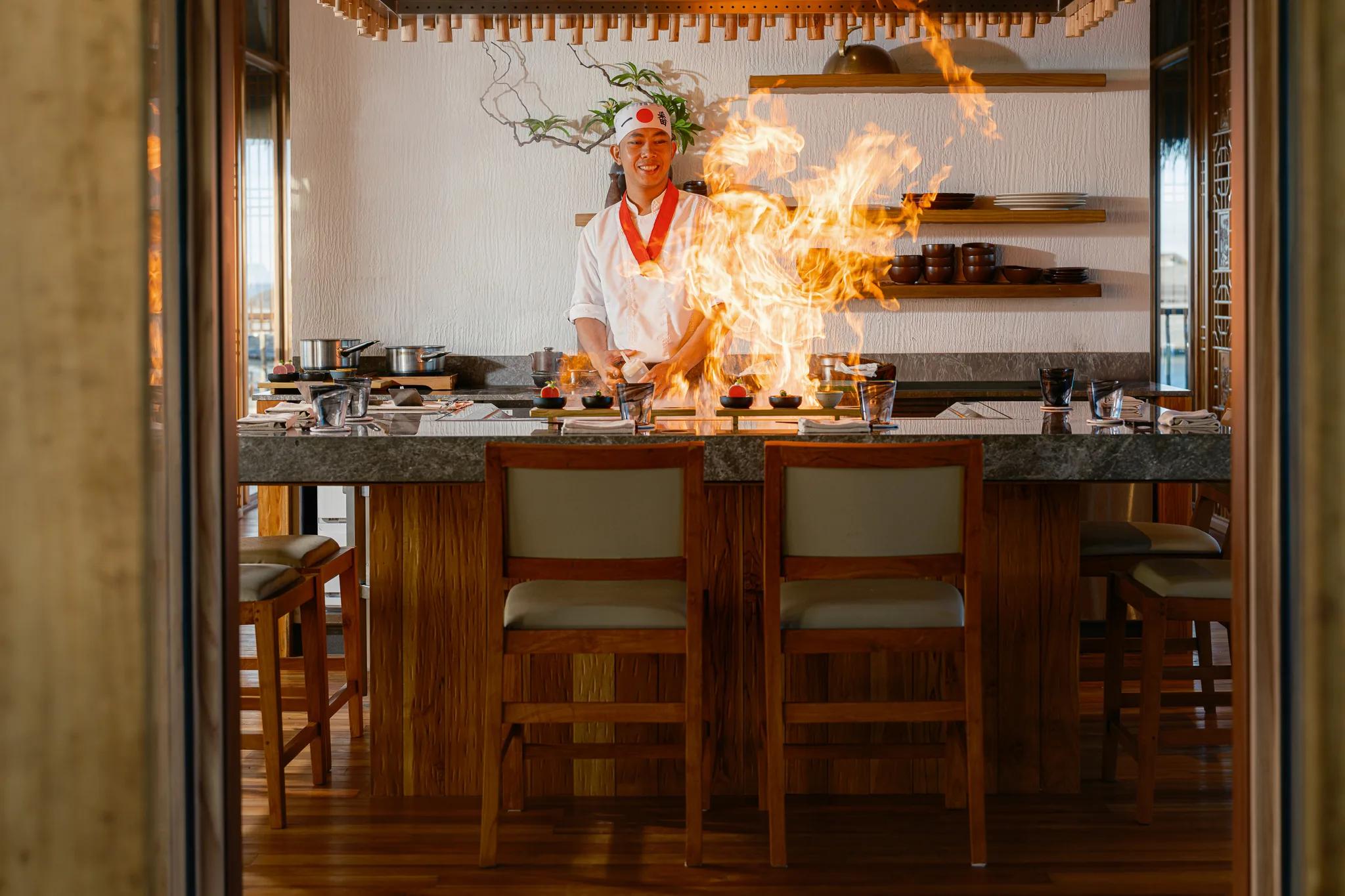 A Kaji chef finishes a dish over an open flame at the teppanyaki counter