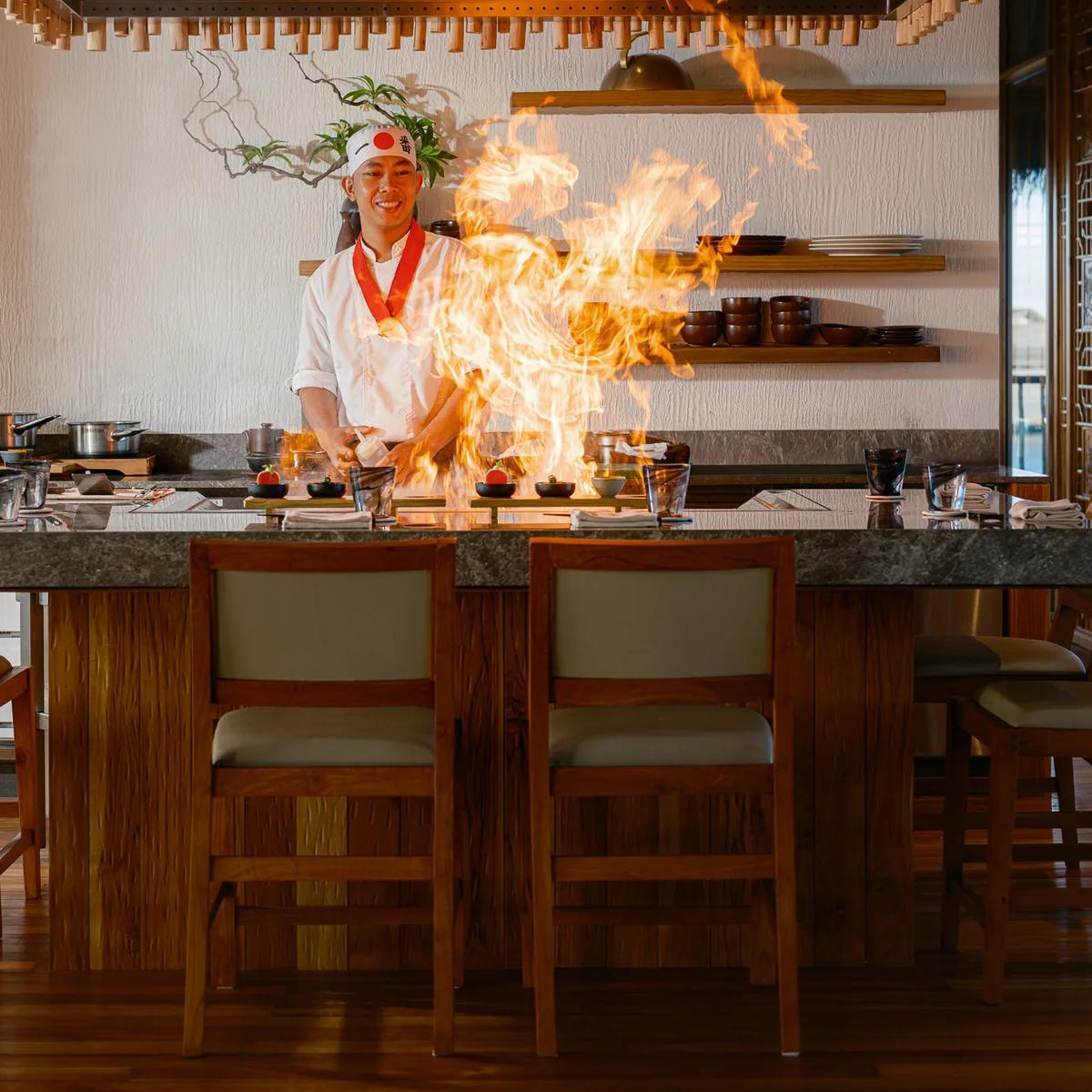 A Kaji chef finishes a dish over an open flame at the teppanyaki counter