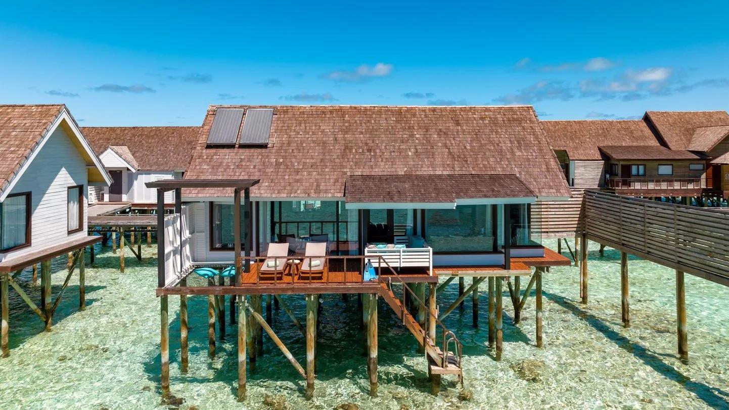 Overwater Wind Villas on stilts above the clear lagoon, with steps leading down to the water