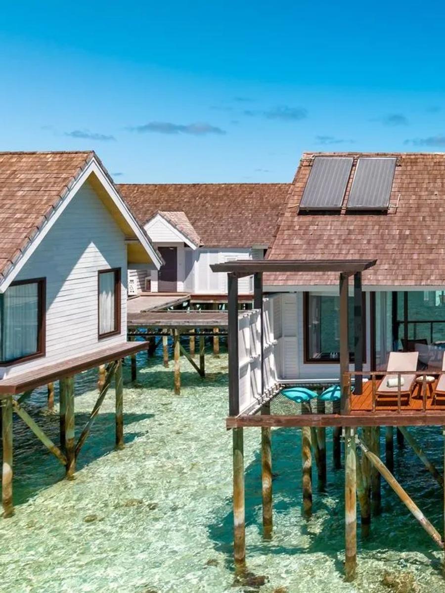 Overwater Wind Villas on stilts above the clear lagoon, with steps leading down to the water