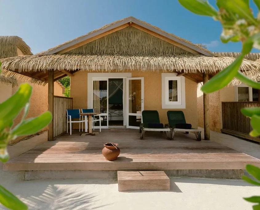 Garden Bungalow exterior with a thatched roof and private terrace, screened by tropical planting