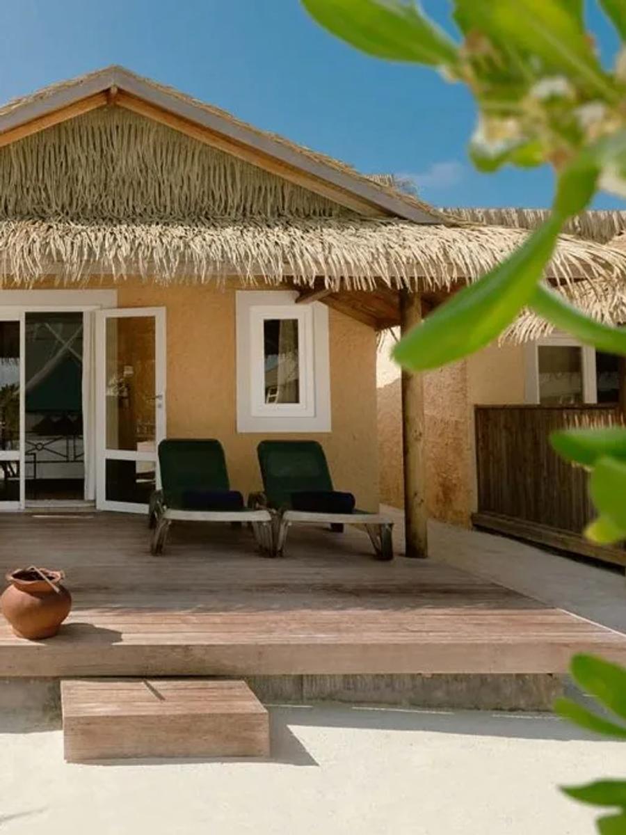 Garden Bungalow exterior with a thatched roof and private terrace, screened by tropical planting
