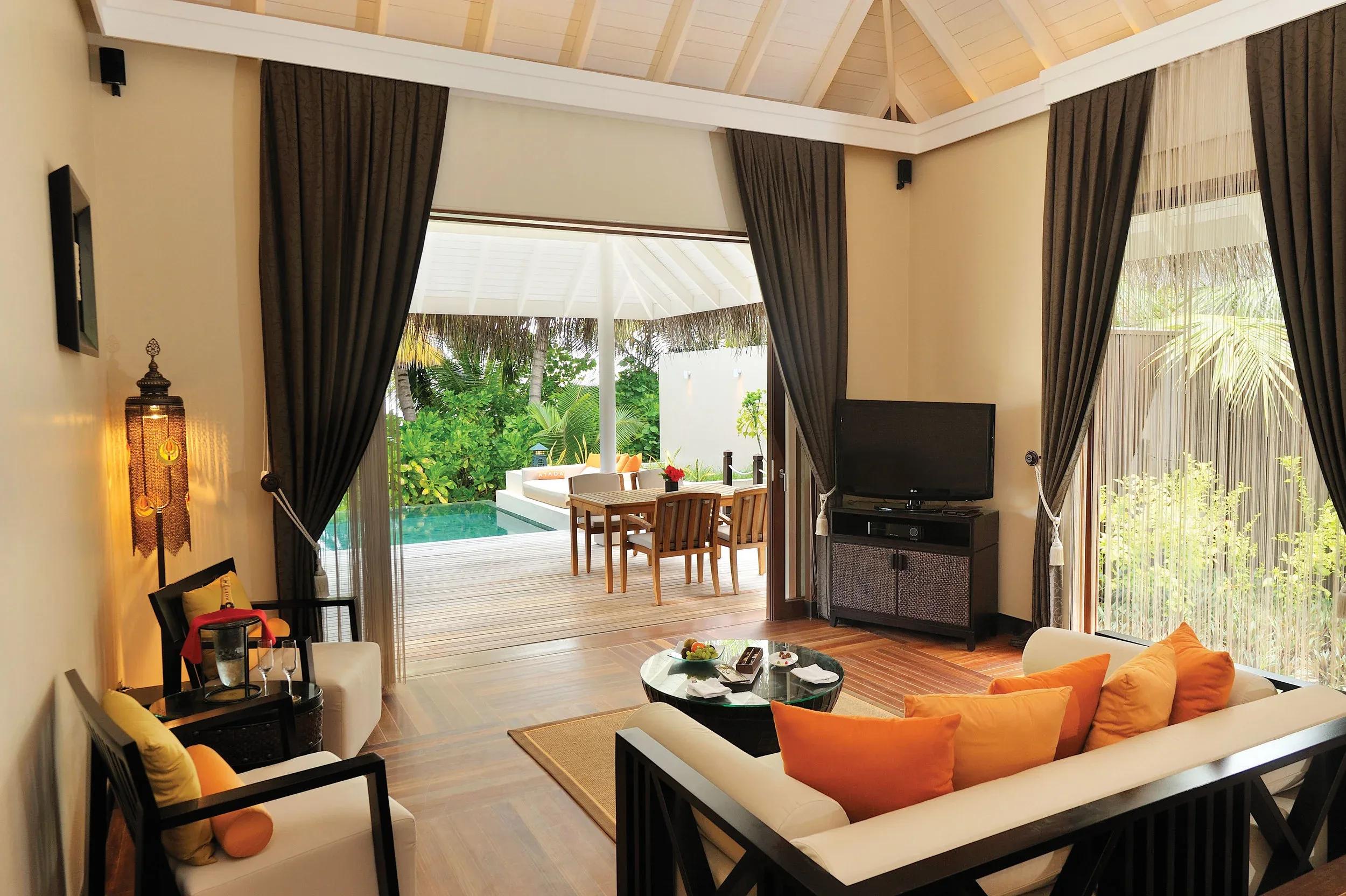A Sunset Beach Suite's living room opening onto its pool deck and dining table